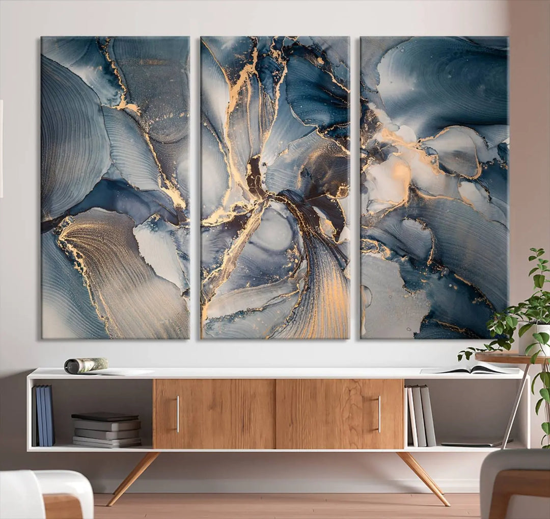 The Abstract Wall Art Canvas Print for Modern Home Decor is a striking feature in the modern living room. It showcases a blue and gold triptych design on museum-quality canvas, complete with a UV-protective coating to ensure long-lasting vibrancy.