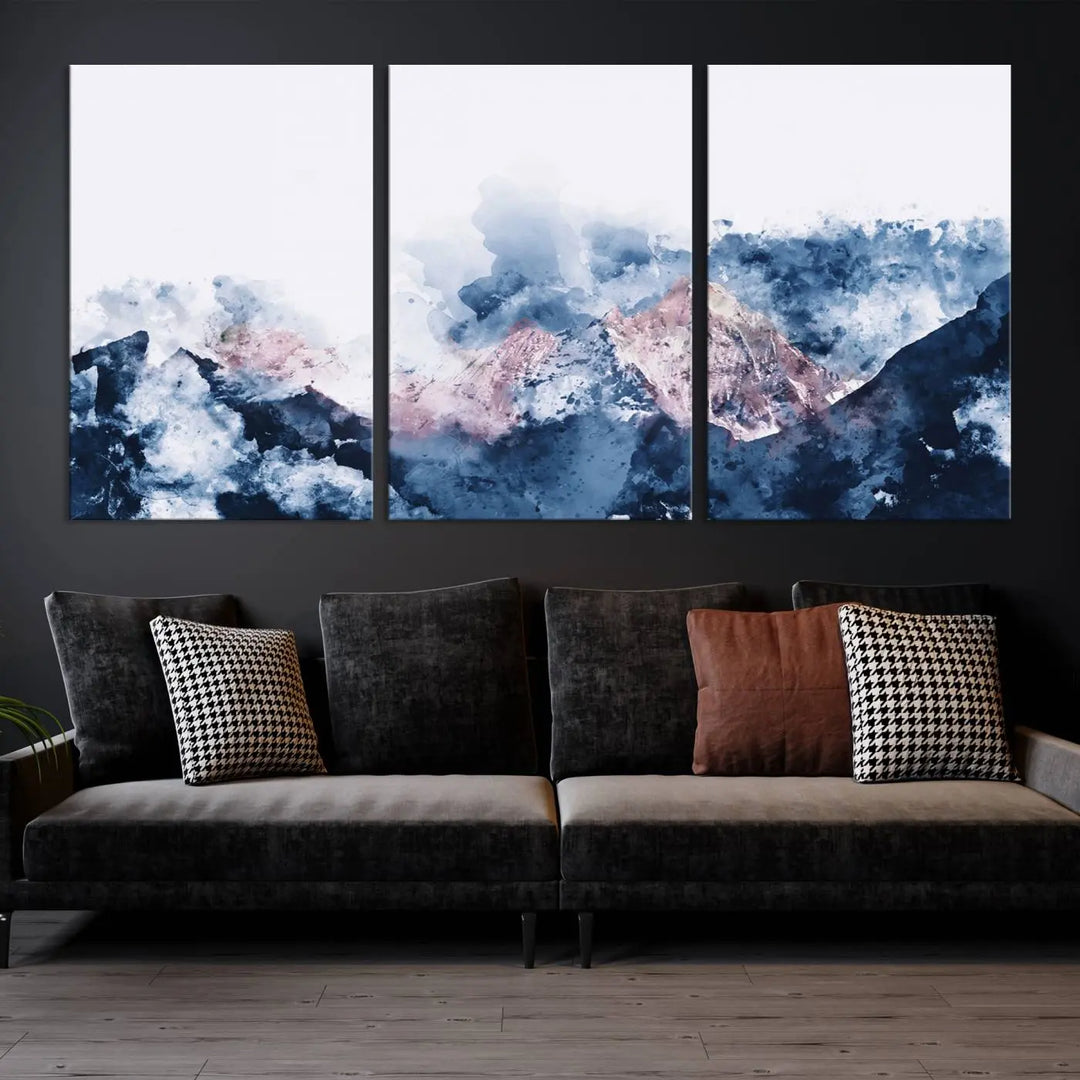 The modern living room features a framed triptych art on a dark wall, complemented by the Abstract Watercolor Mountain Landscape Art Canvas Print, which adds elegance and depth to the space.