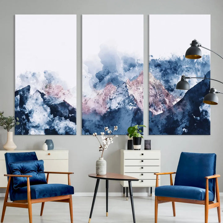 The modern living room features a framed triptych art on a dark wall, complemented by the Abstract Watercolor Mountain Landscape Art Canvas Print, which adds elegance and depth to the space.