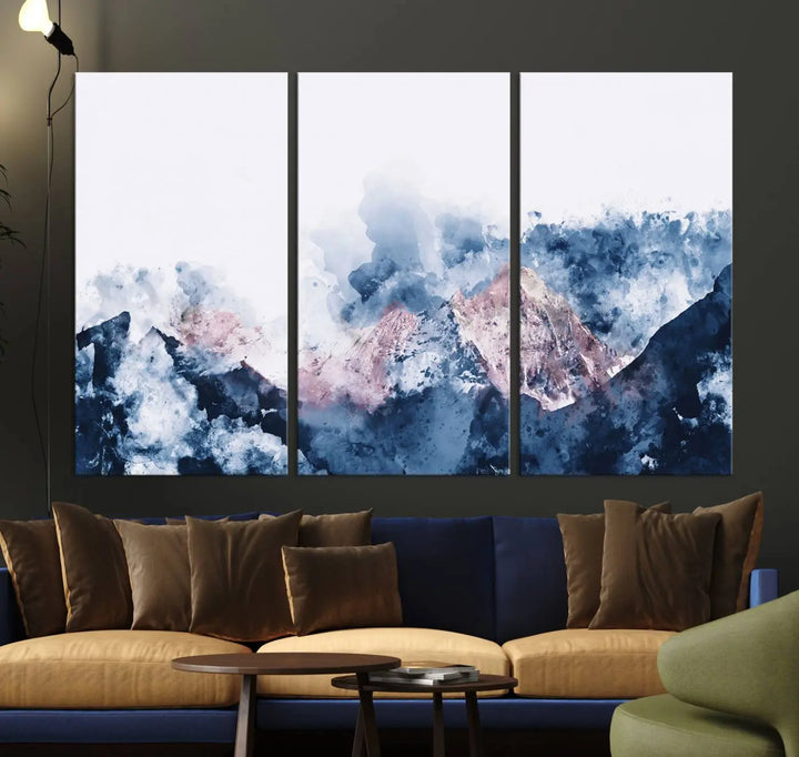 The modern living room features a framed triptych art on a dark wall, complemented by the Abstract Watercolor Mountain Landscape Art Canvas Print, which adds elegance and depth to the space.