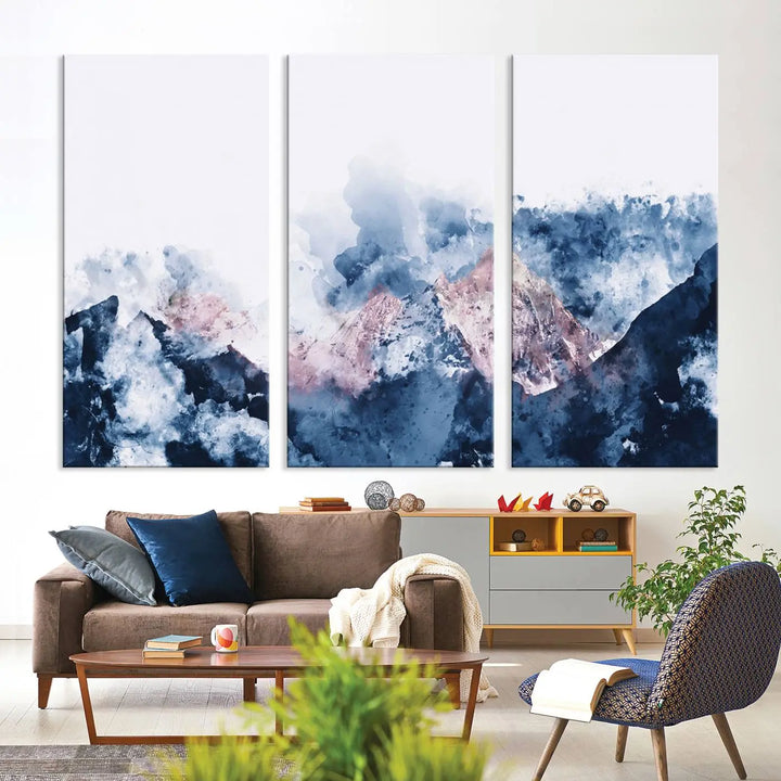 The modern living room features a framed triptych art on a dark wall, complemented by the Abstract Watercolor Mountain Landscape Art Canvas Print, which adds elegance and depth to the space.