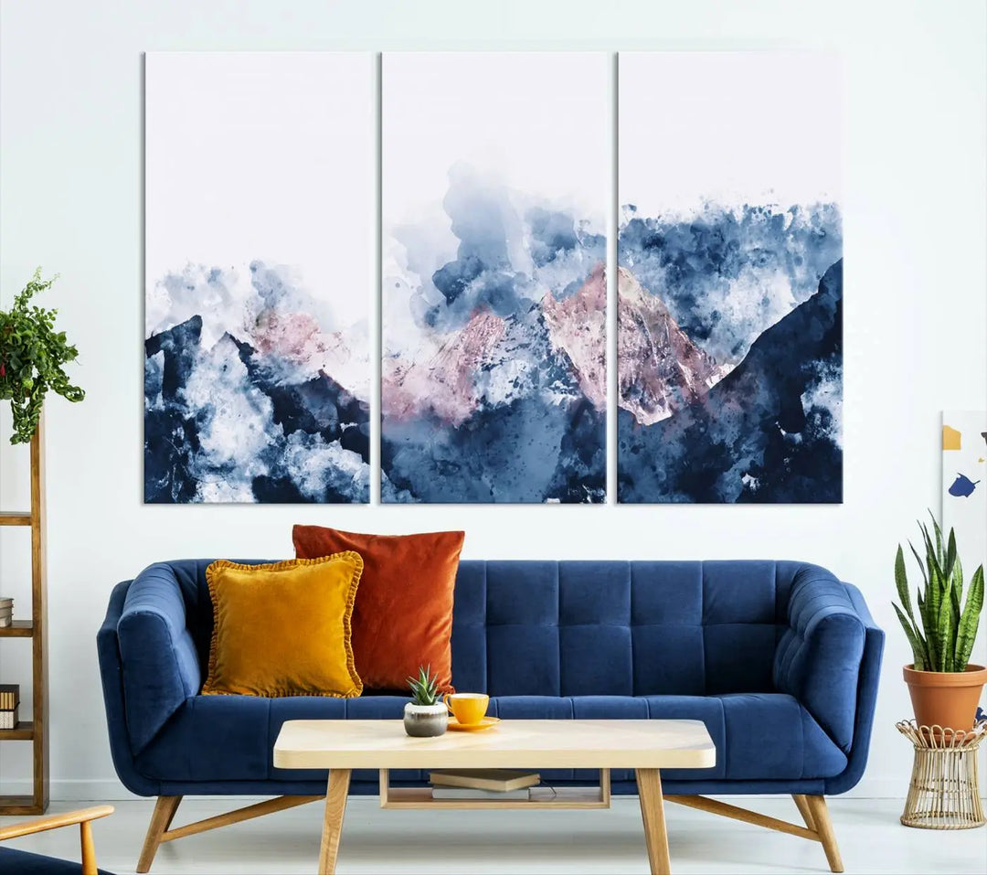 The modern living room features a framed triptych art on a dark wall, complemented by the Abstract Watercolor Mountain Landscape Art Canvas Print, which adds elegance and depth to the space.