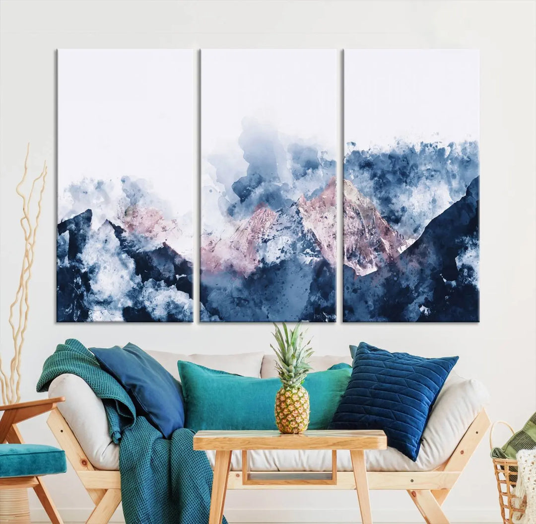 The modern living room features a framed triptych art on a dark wall, complemented by the Abstract Watercolor Mountain Landscape Art Canvas Print, which adds elegance and depth to the space.