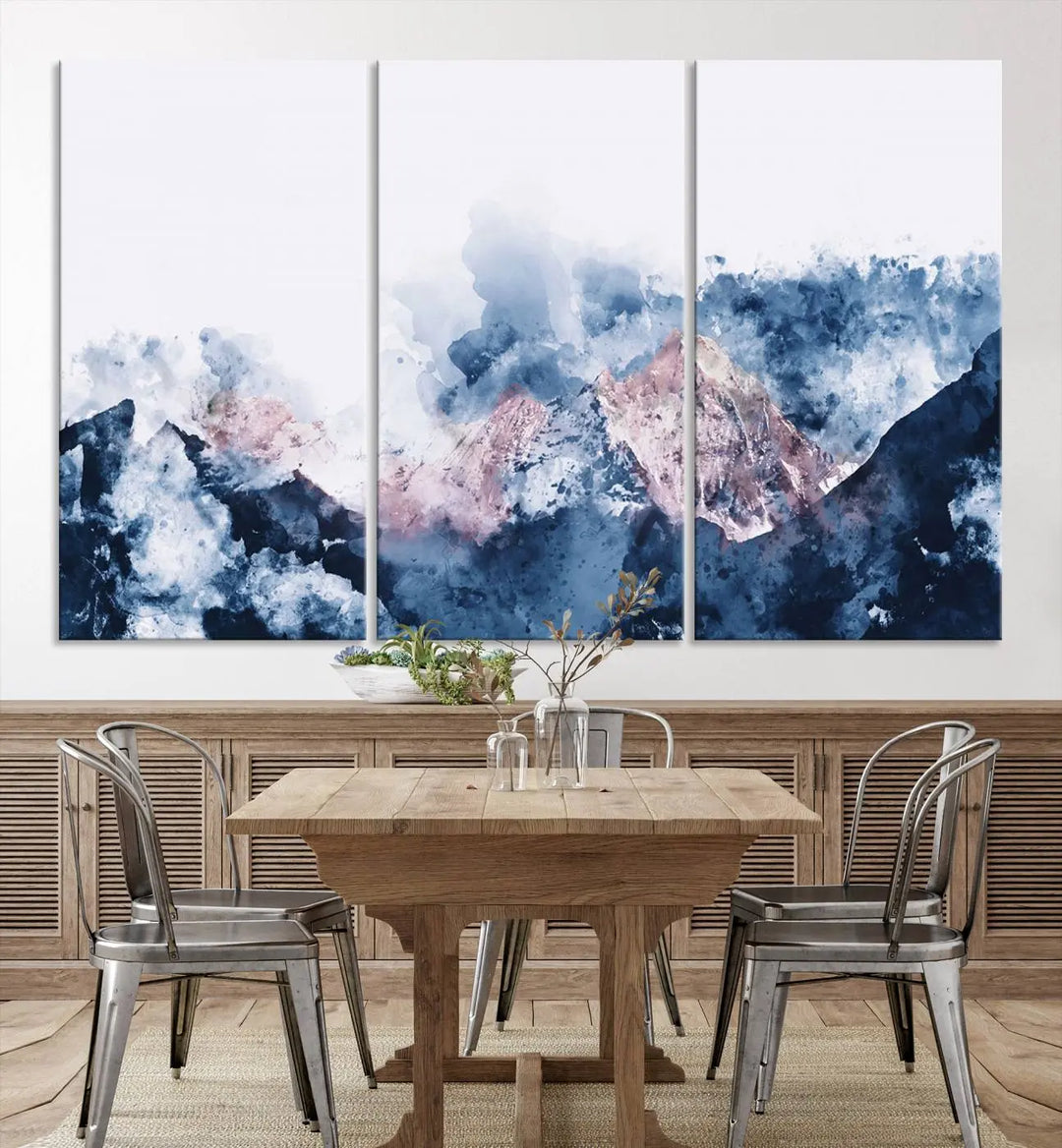 The modern living room features a framed triptych art on a dark wall, complemented by the Abstract Watercolor Mountain Landscape Art Canvas Print, which adds elegance and depth to the space.