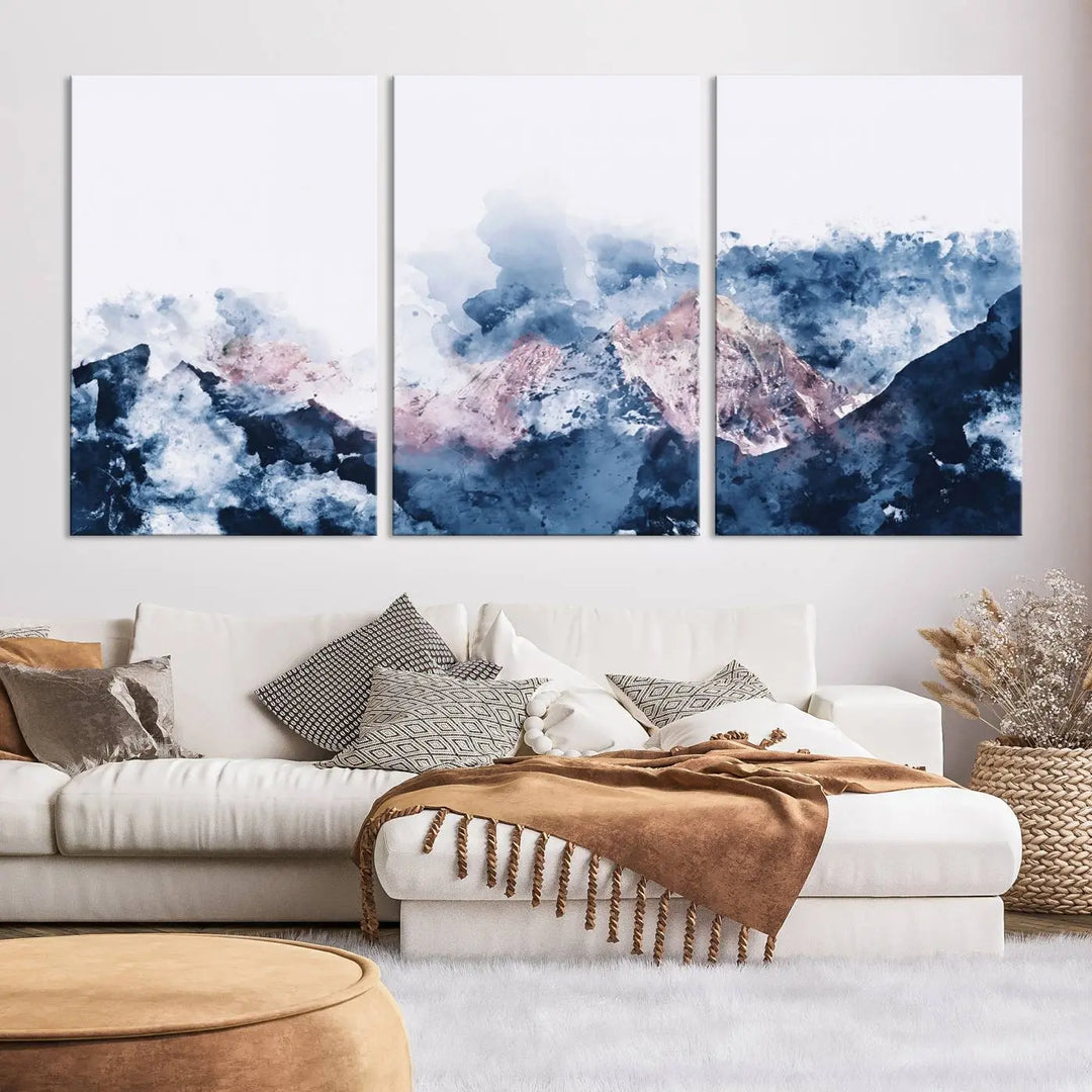 The modern living room features a framed triptych art on a dark wall, complemented by the Abstract Watercolor Mountain Landscape Art Canvas Print, which adds elegance and depth to the space.