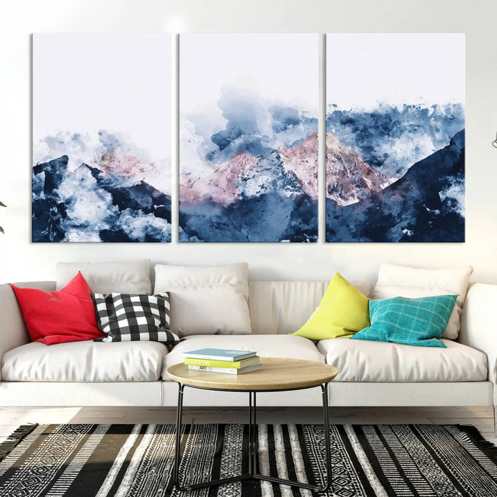 The modern living room features a framed triptych art on a dark wall, complemented by the Abstract Watercolor Mountain Landscape Art Canvas Print, which adds elegance and depth to the space.