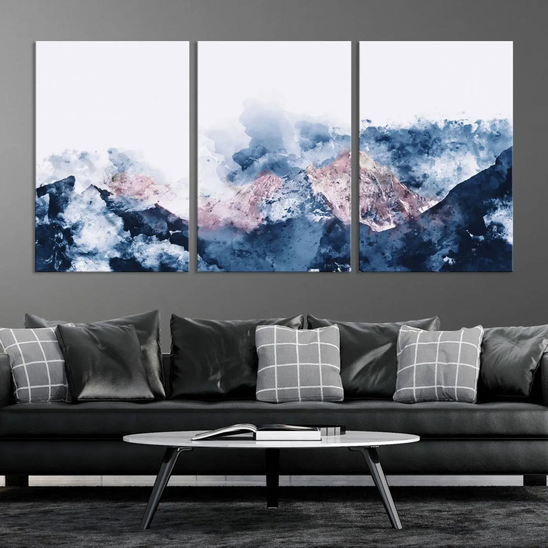 The modern living room features a framed triptych art on a dark wall, complemented by the Abstract Watercolor Mountain Landscape Art Canvas Print, which adds elegance and depth to the space.