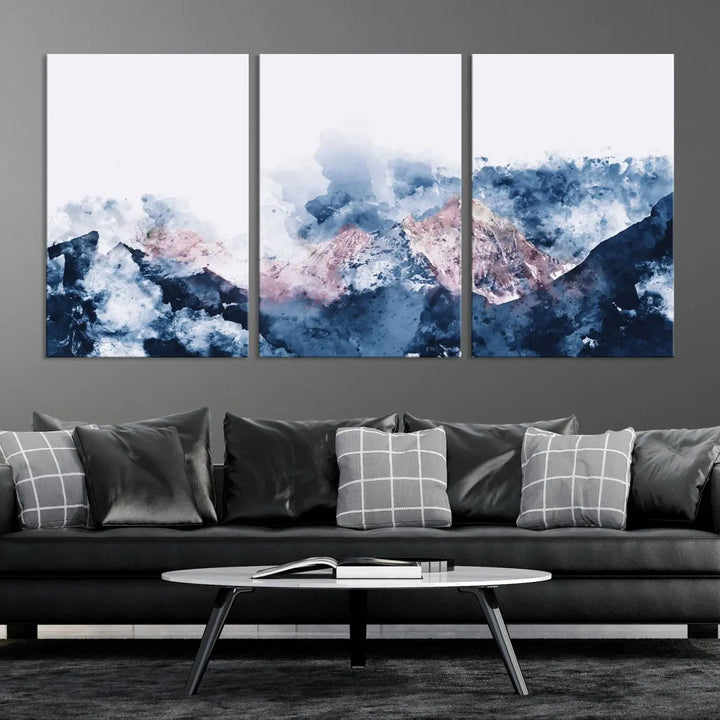 The modern living room features a framed triptych art on a dark wall, complemented by the Abstract Watercolor Mountain Landscape Art Canvas Print, which adds elegance and depth to the space.