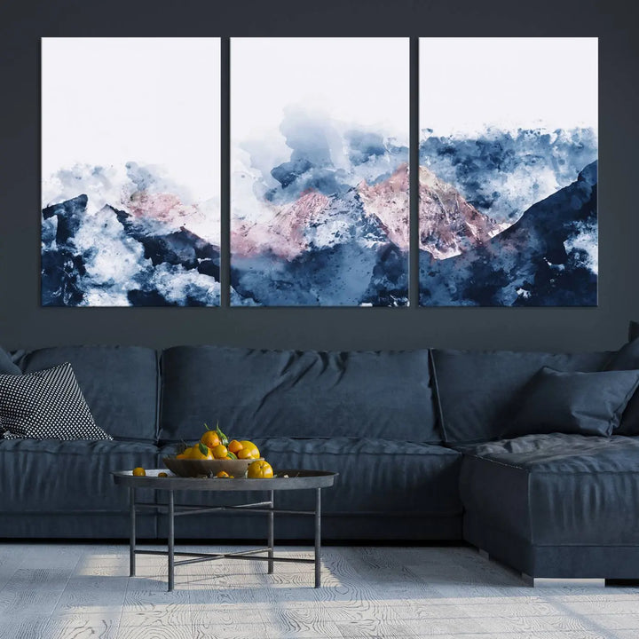 The modern living room features a framed triptych art on a dark wall, complemented by the Abstract Watercolor Mountain Landscape Art Canvas Print, which adds elegance and depth to the space.