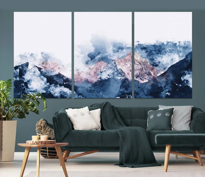 The modern living room features a framed triptych art on a dark wall, complemented by the Abstract Watercolor Mountain Landscape Art Canvas Print, which adds elegance and depth to the space.