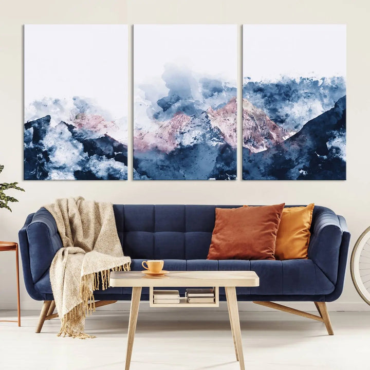 The modern living room features a framed triptych art on a dark wall, complemented by the Abstract Watercolor Mountain Landscape Art Canvas Print, which adds elegance and depth to the space.