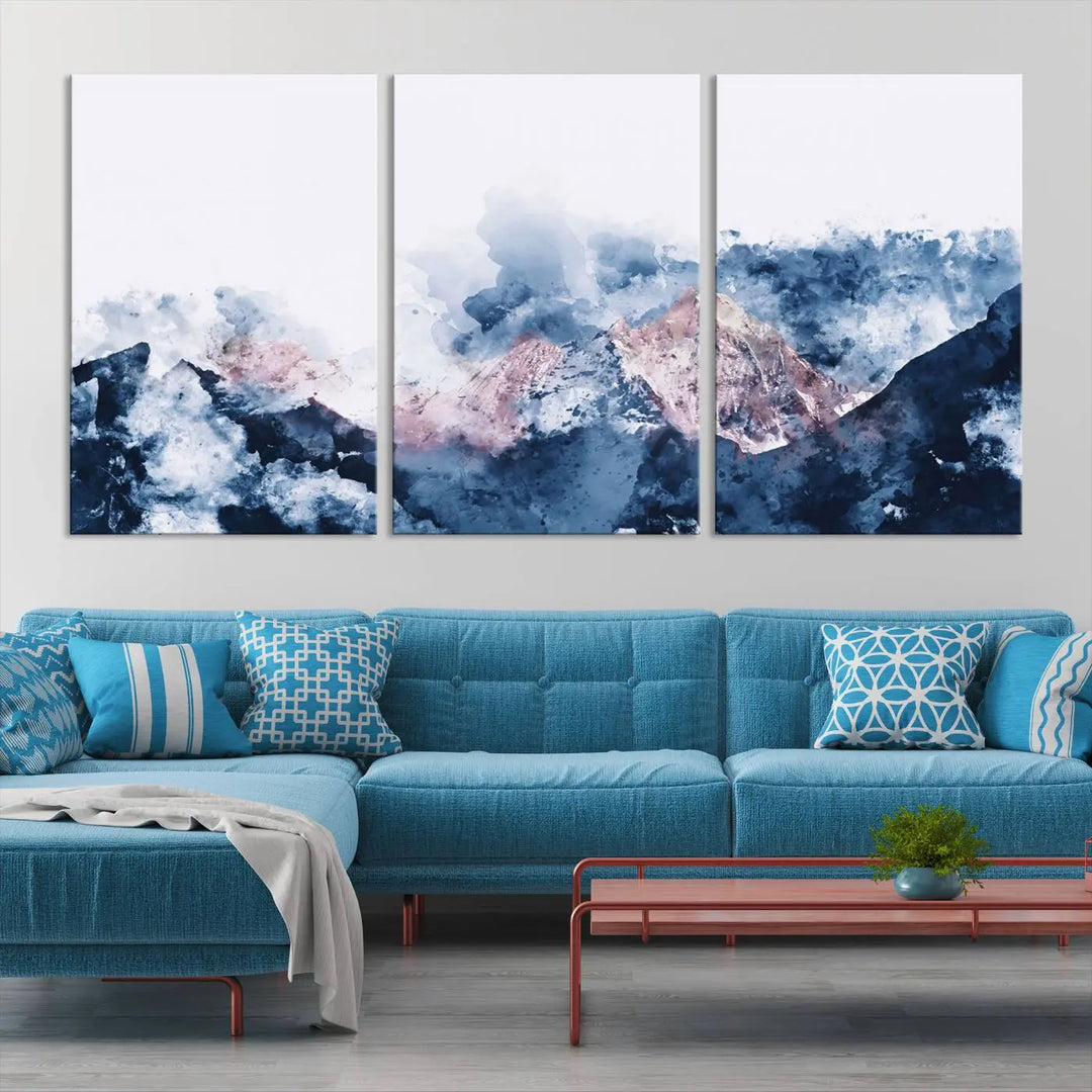 The modern living room features a framed triptych art on a dark wall, complemented by the Abstract Watercolor Mountain Landscape Art Canvas Print, which adds elegance and depth to the space.