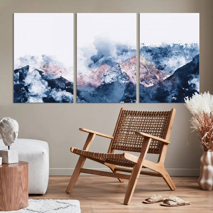 The modern living room features a framed triptych art on a dark wall, complemented by the Abstract Watercolor Mountain Landscape Art Canvas Print, which adds elegance and depth to the space.