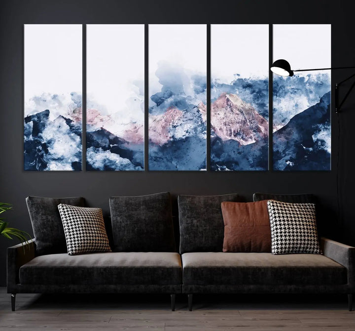 The modern living room features a framed triptych art on a dark wall, complemented by the Abstract Watercolor Mountain Landscape Art Canvas Print, which adds elegance and depth to the space.