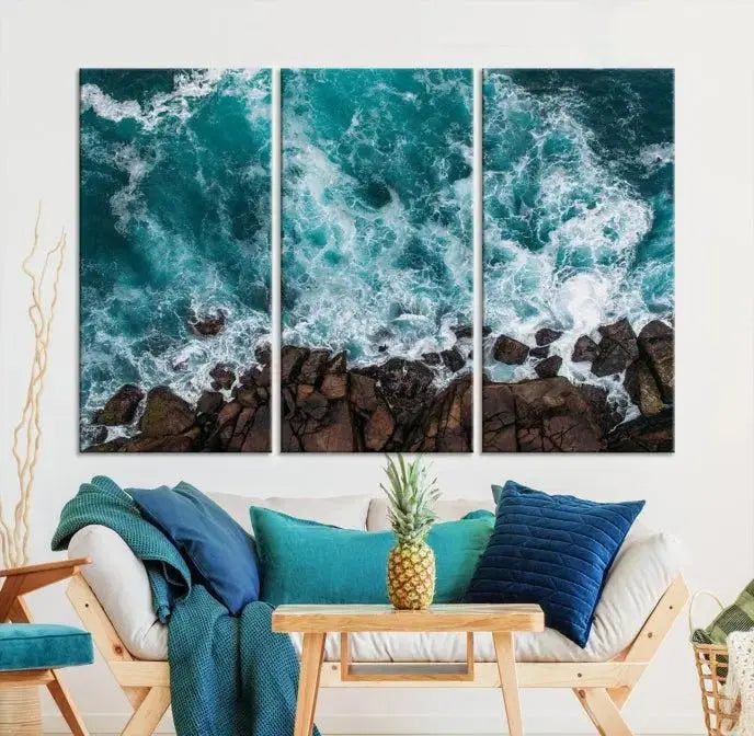 The Aerial Ocean Waves Wall Art Canvas Print is showcased on gallery-wrapped, museum-quality canvases, depicting a triptych of ocean waves crashing on rocks.