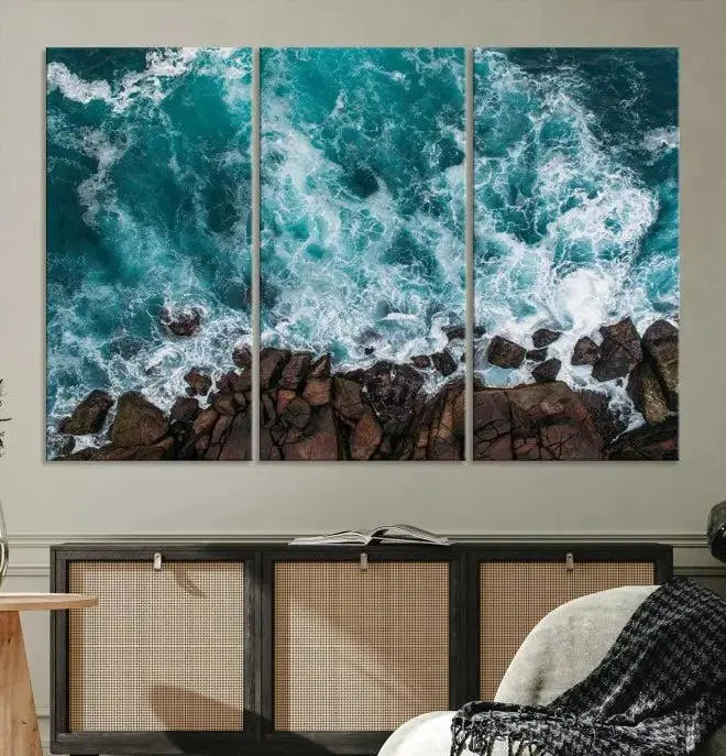 The Aerial Ocean Waves Wall Art Canvas Print is showcased on gallery-wrapped, museum-quality canvases, depicting a triptych of ocean waves crashing on rocks.