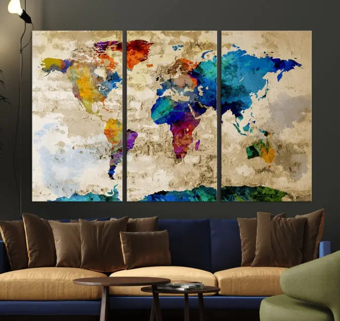 A three-panel "Watercolor Wall Art World Map w/ Antarctica Canvas Print" on museum-quality canvas features vibrant colors and is ready to hang in a dimly lit living room.