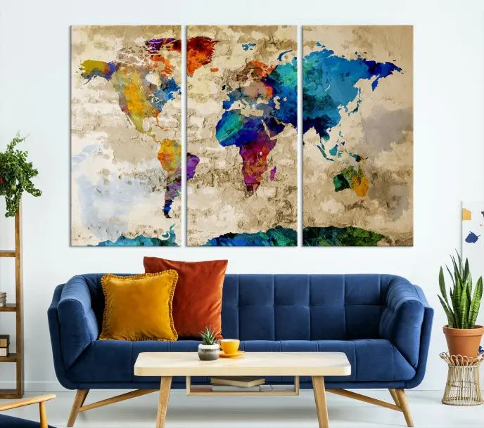 A three-panel "Watercolor Wall Art World Map w/ Antarctica Canvas Print" on museum-quality canvas features vibrant colors and is ready to hang in a dimly lit living room.