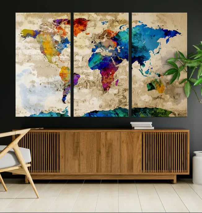 A three-panel "Watercolor Wall Art World Map w/ Antarctica Canvas Print" on museum-quality canvas features vibrant colors and is ready to hang in a dimly lit living room.