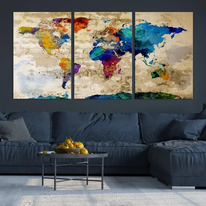 A three-panel "Watercolor Wall Art World Map w/ Antarctica Canvas Print" on museum-quality canvas features vibrant colors and is ready to hang in a dimly lit living room.