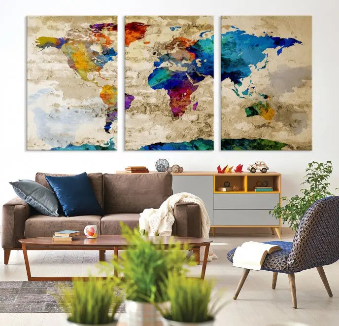 A three-panel "Watercolor Wall Art World Map w/ Antarctica Canvas Print" on museum-quality canvas features vibrant colors and is ready to hang in a dimly lit living room.