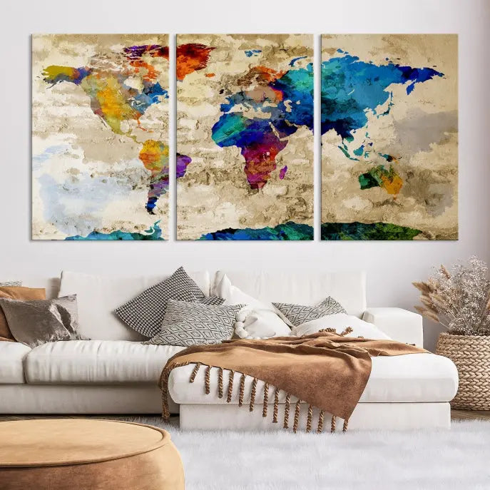 A three-panel "Watercolor Wall Art World Map w/ Antarctica Canvas Print" on museum-quality canvas features vibrant colors and is ready to hang in a dimly lit living room.