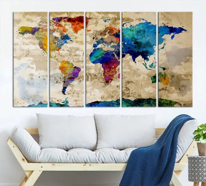 A three-panel "Watercolor Wall Art World Map w/ Antarctica Canvas Print" on museum-quality canvas features vibrant colors and is ready to hang in a dimly lit living room.