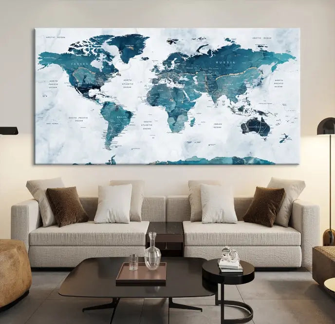 A Push Pin World Map with Antarctica, printed on museum-quality canvas portraying blue oceans, is displayed as a triptych above a dark wall.