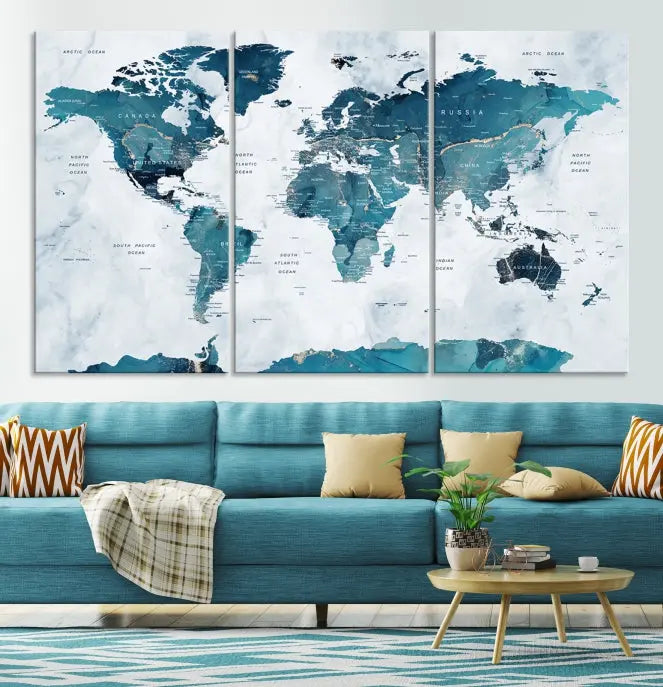 A Push Pin World Map with Antarctica, printed on museum-quality canvas portraying blue oceans, is displayed as a triptych above a dark wall.