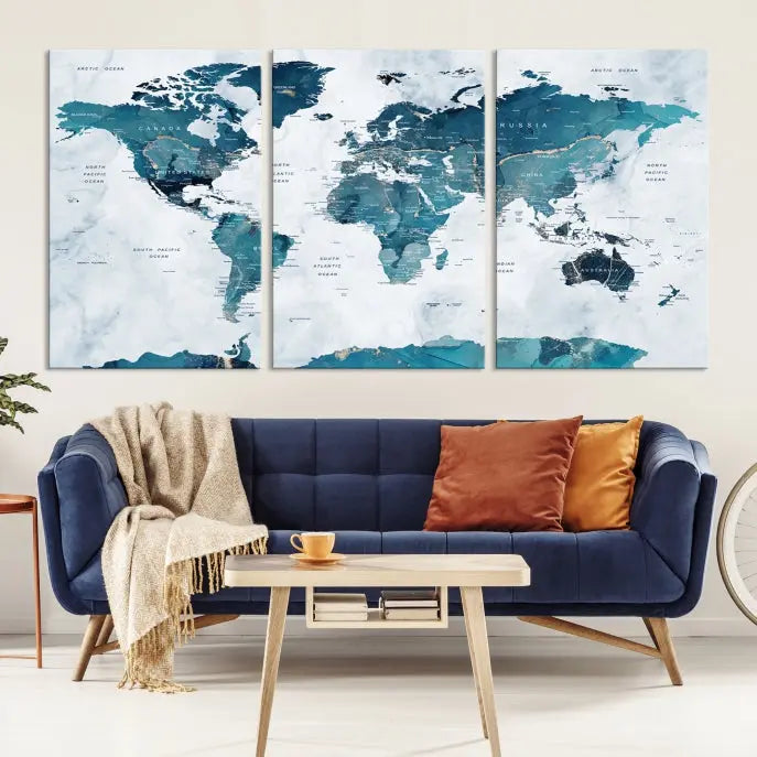 A Push Pin World Map with Antarctica, printed on museum-quality canvas portraying blue oceans, is displayed as a triptych above a dark wall.