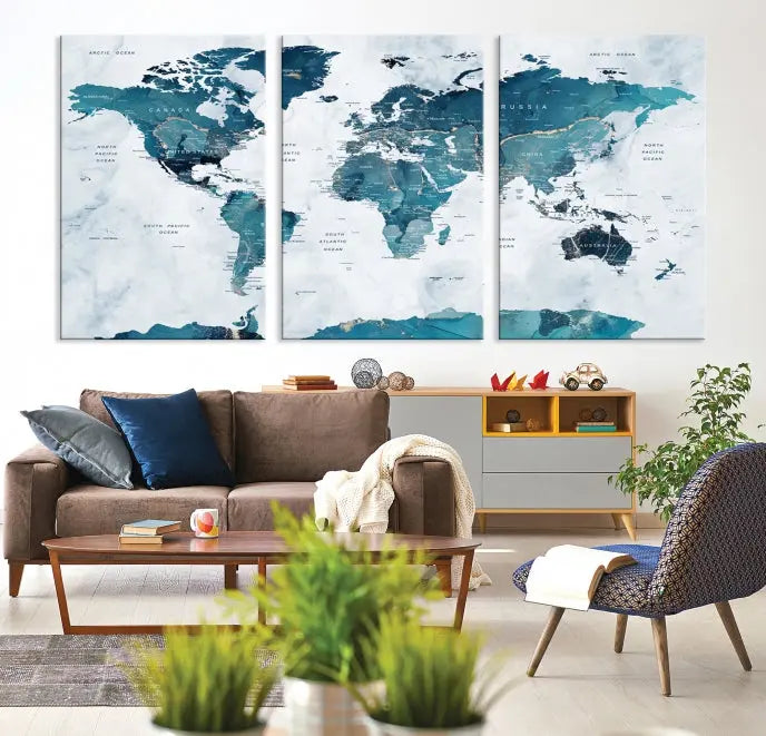 A Push Pin World Map with Antarctica, printed on museum-quality canvas portraying blue oceans, is displayed as a triptych above a dark wall.