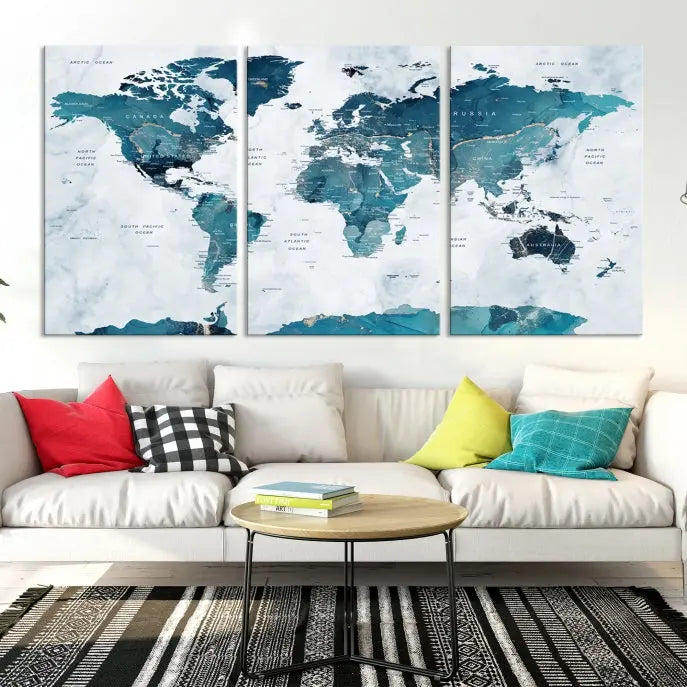 A Push Pin World Map with Antarctica, printed on museum-quality canvas portraying blue oceans, is displayed as a triptych above a dark wall.