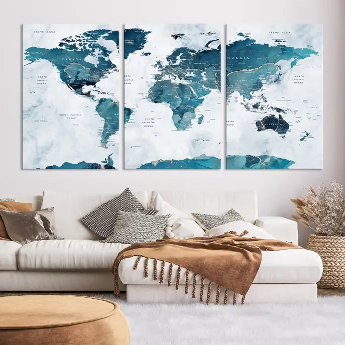 A Push Pin World Map with Antarctica, printed on museum-quality canvas portraying blue oceans, is displayed as a triptych above a dark wall.