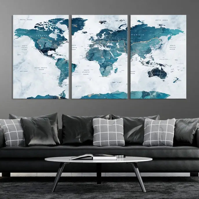 A Push Pin World Map with Antarctica, printed on museum-quality canvas portraying blue oceans, is displayed as a triptych above a dark wall.