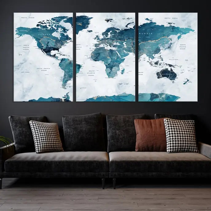 A Push Pin World Map with Antarctica, printed on museum-quality canvas portraying blue oceans, is displayed as a triptych above a dark wall.