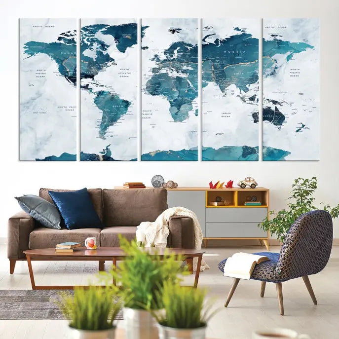 A Push Pin World Map with Antarctica, printed on museum-quality canvas portraying blue oceans, is displayed as a triptych above a dark wall.