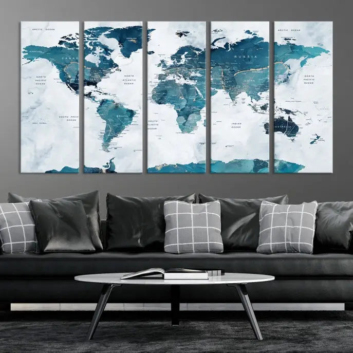 A Push Pin World Map with Antarctica, printed on museum-quality canvas portraying blue oceans, is displayed as a triptych above a dark wall.