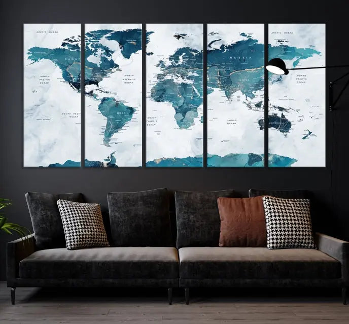 A Push Pin World Map with Antarctica, printed on museum-quality canvas portraying blue oceans, is displayed as a triptych above a dark wall.