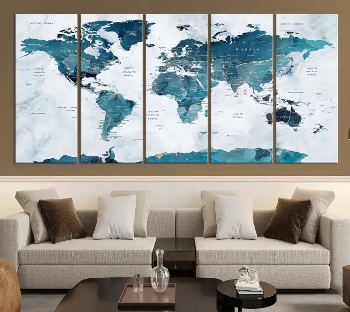 A Push Pin World Map with Antarctica, printed on museum-quality canvas portraying blue oceans, is displayed as a triptych above a dark wall.