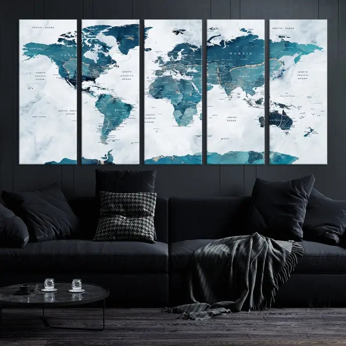 A Push Pin World Map with Antarctica, printed on museum-quality canvas portraying blue oceans, is displayed as a triptych above a dark wall.