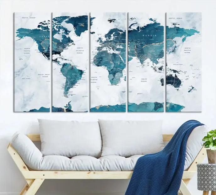 A Push Pin World Map with Antarctica, printed on museum-quality canvas portraying blue oceans, is displayed as a triptych above a dark wall.