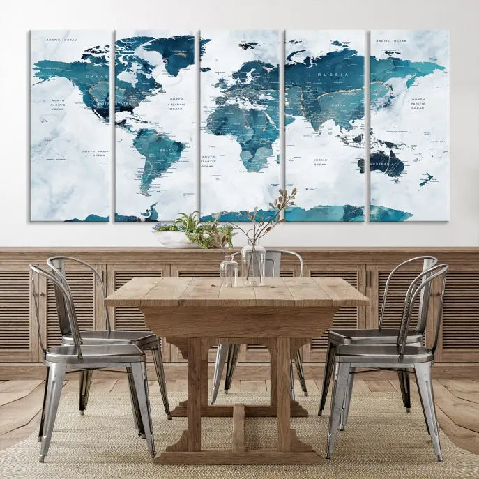 A Push Pin World Map with Antarctica, printed on museum-quality canvas portraying blue oceans, is displayed as a triptych above a dark wall.