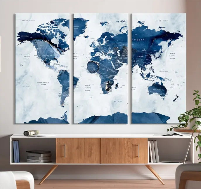 The Navy Blue World Map with Antarctica Wall Art Canvas Print, featuring a stunning blend of blue and white on a museum-quality canvas, elegantly adorns a dark wall. This ready-to-hang masterpiece enhances the room's sophisticated ambiance.