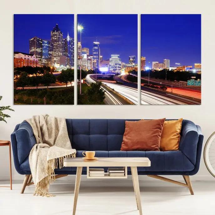 The living room features an Atlanta City Lights Night Blue Skyline canvas print on the wall. This museum-quality triptych showcases a highway and skyscrapers at night, comes with a UV-protective coating, and is ready to hang, adding both elegance and ease to your space.