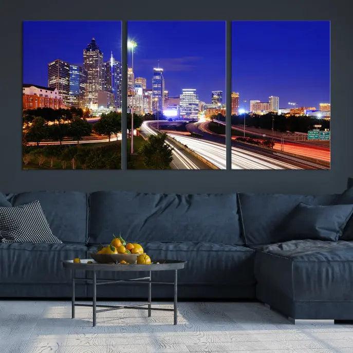 The living room features an Atlanta City Lights Night Blue Skyline canvas print on the wall. This museum-quality triptych showcases a highway and skyscrapers at night, comes with a UV-protective coating, and is ready to hang, adding both elegance and ease to your space.