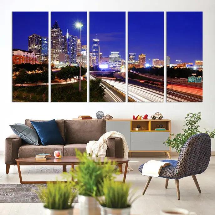 The living room features an Atlanta City Lights Night Blue Skyline canvas print on the wall. This museum-quality triptych showcases a highway and skyscrapers at night, comes with a UV-protective coating, and is ready to hang, adding both elegance and ease to your space.