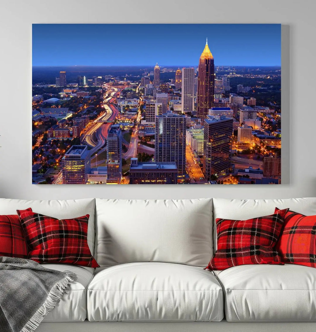 The triptych titled "Atlanta Wall Art Canvas Print" decorates the wall in a modern living room. This museum-quality artwork of a cityscape at night is ready to hang and features a UV-protective coating that ensures lasting vibrancy and elegance.