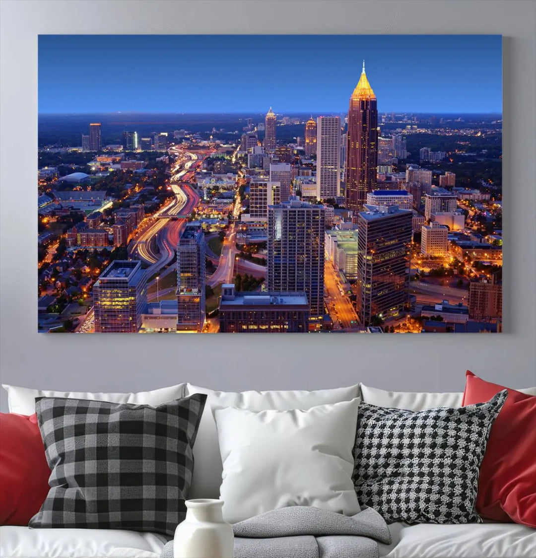 The triptych titled "Atlanta Wall Art Canvas Print" decorates the wall in a modern living room. This museum-quality artwork of a cityscape at night is ready to hang and features a UV-protective coating that ensures lasting vibrancy and elegance.