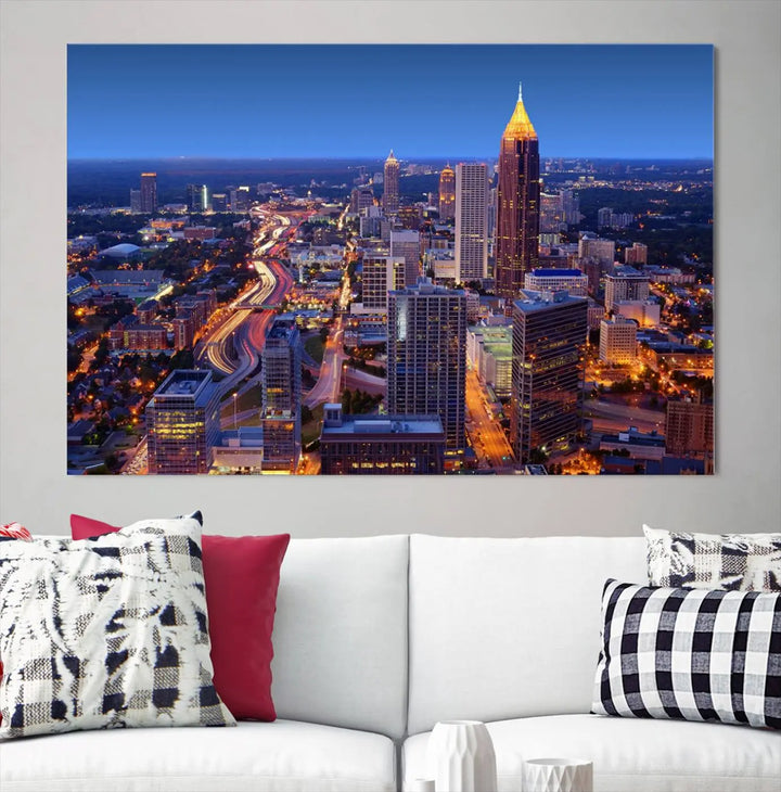 The triptych titled "Atlanta Wall Art Canvas Print" decorates the wall in a modern living room. This museum-quality artwork of a cityscape at night is ready to hang and features a UV-protective coating that ensures lasting vibrancy and elegance.