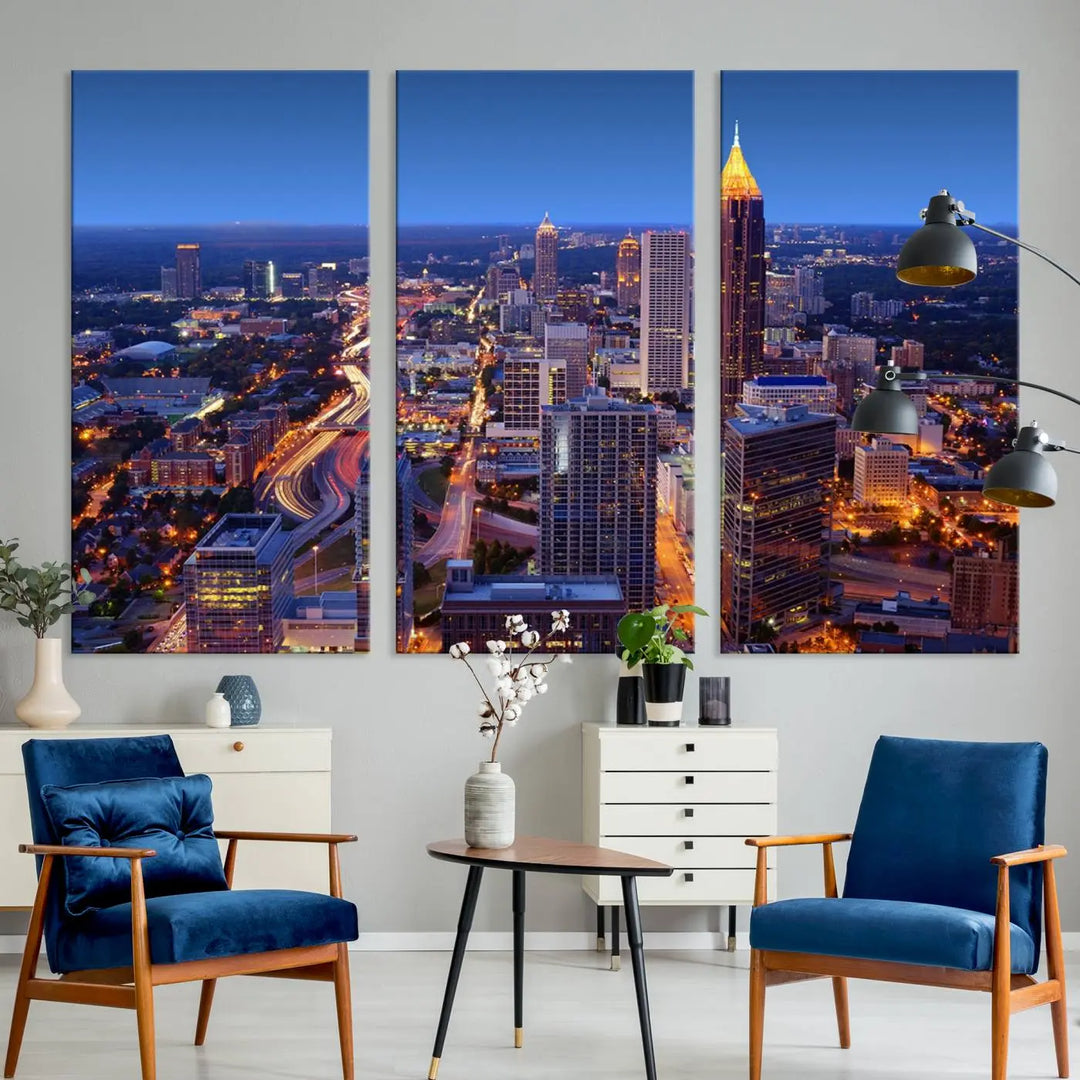 The triptych titled "Atlanta Wall Art Canvas Print" decorates the wall in a modern living room. This museum-quality artwork of a cityscape at night is ready to hang and features a UV-protective coating that ensures lasting vibrancy and elegance.